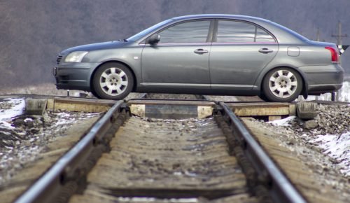 The car is in motion. The car crosses the railway.